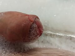 Close up pissing cock from the foam in bath tube